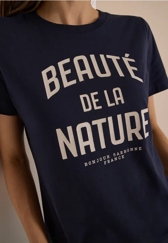 Femme portant un t-shirt bleu marine avec inscription blanche "Beauté de la Nature".