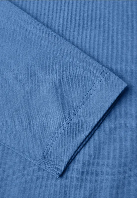 Nahaufnahme eines blauen T-Shirt-Ärmels mit feiner Naht und gefaltetem Stoff.