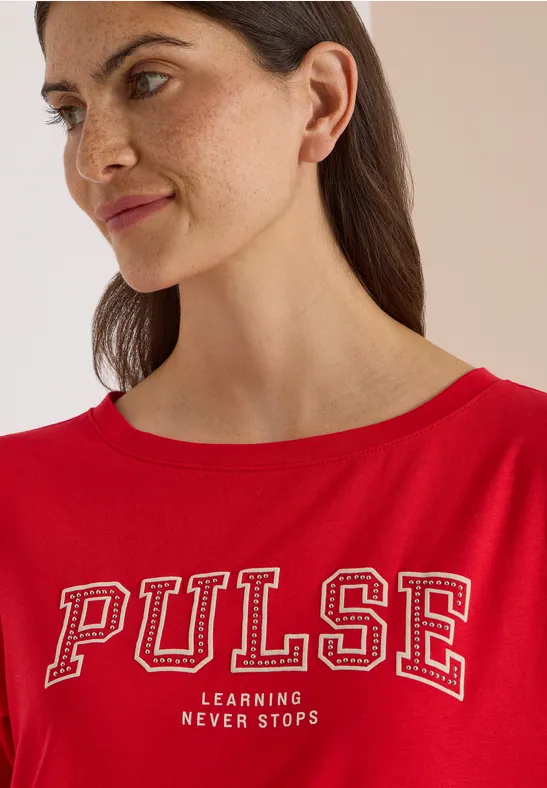 Femme en t-shirt rouge 'PULSE Learning never stops', gros plan, regard de côté