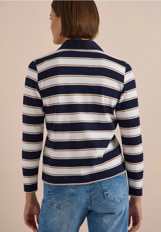 Vue de dos d'une personne portant un polo rayé bleu marine et blanc à manches longues et un jean bleu sur fond beige.