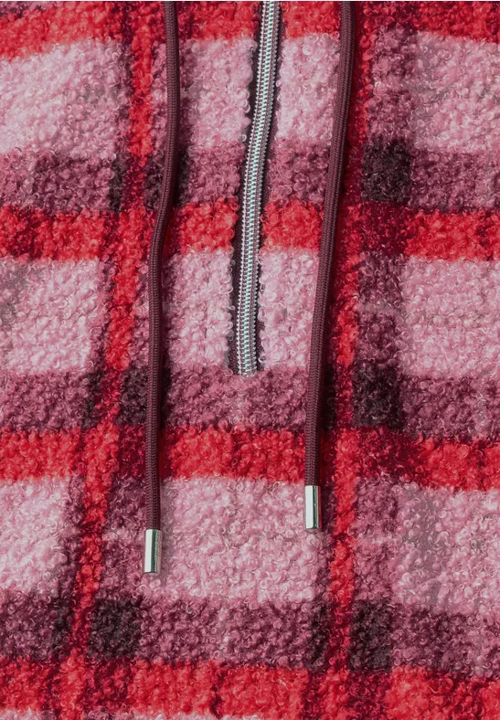 Nahaufnahme eines flauschigen, rot-rosa karierten Fleece-Hoodies mit Kordelzug.
