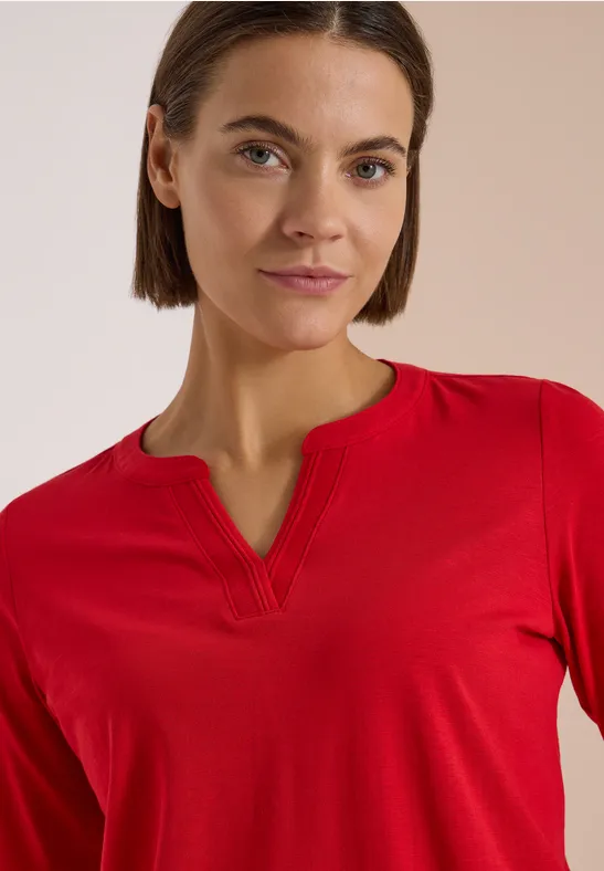Kobieta w czerwonej bluzce, średniej długości brązowe włosy, naturalny look