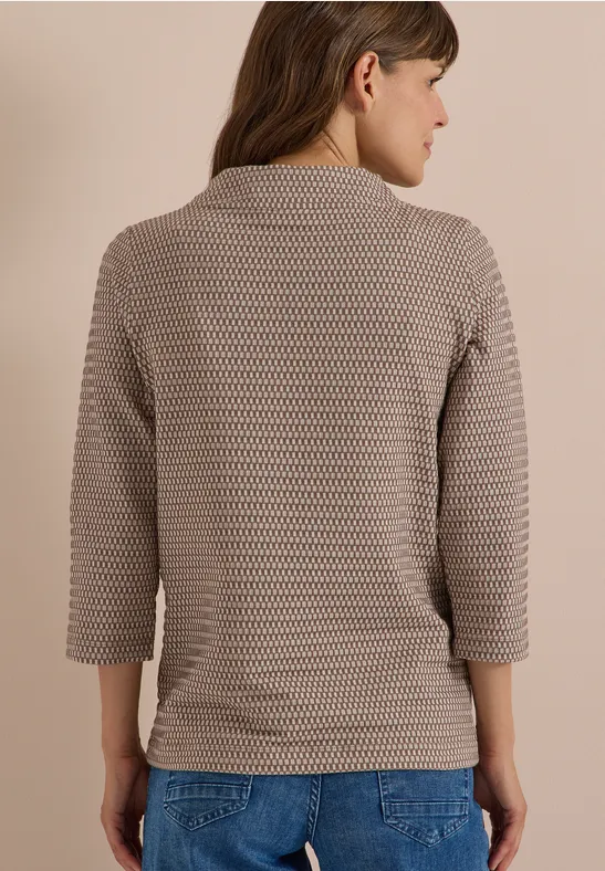 Frau von hinten trägt hellbraunen Waffelstrickpullover mit 3/4-Ärmeln und Jeans.