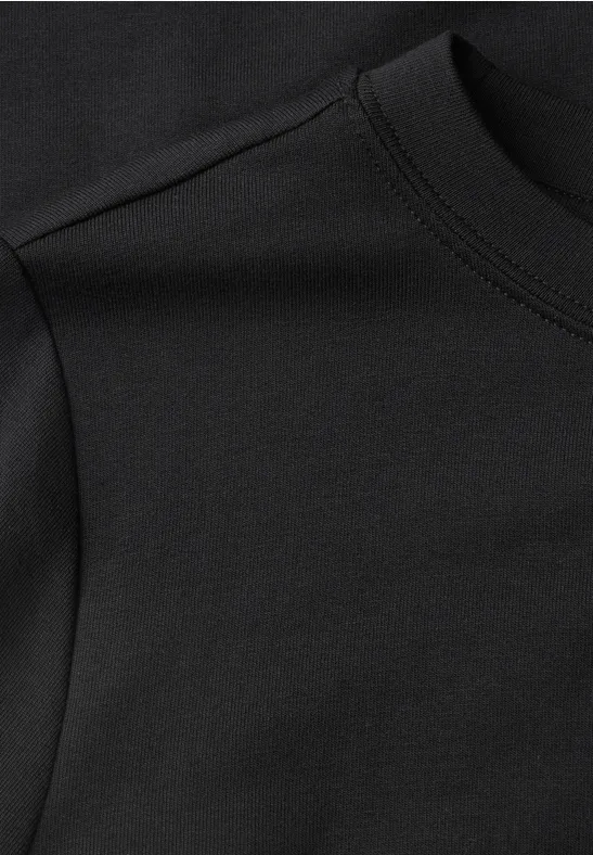 Close-up van een zwart katoenen T-shirt in jersey met ronde hals en zichtbare stiksels.