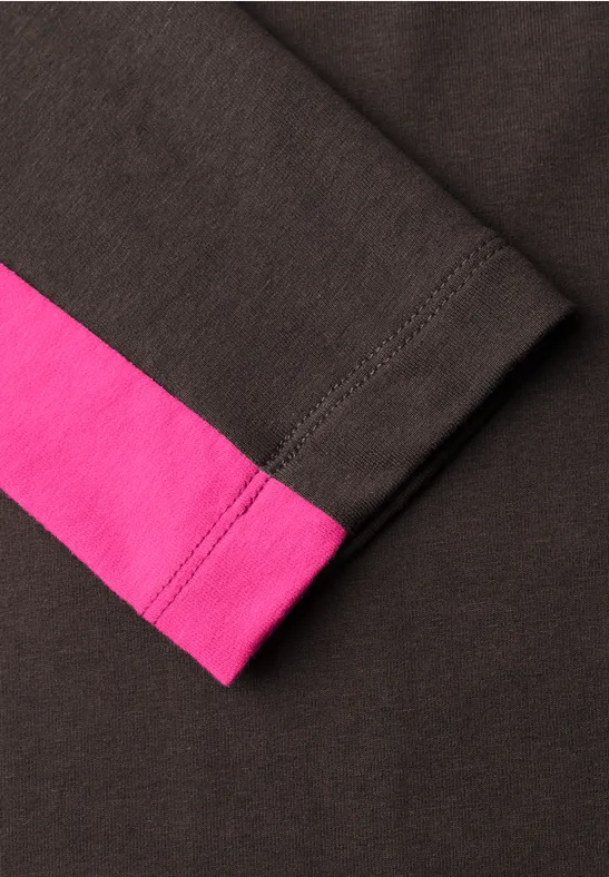 Nahaufnahme eines schwarzen Ärmelendes mit rosa Streifen.