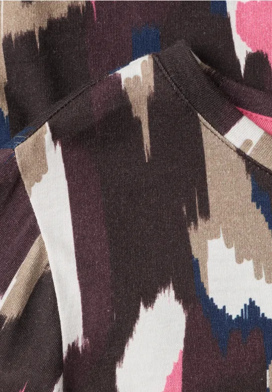 Nahaufnahme eines abstrakten Musters in Braun, Beige, Weiß, Blau und Rosa auf Stoff mit sichtbarer Naht und Tasche.