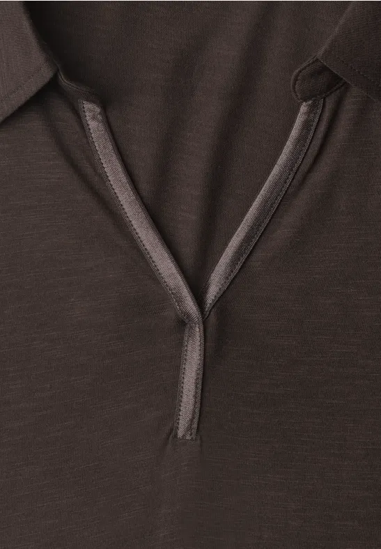 Nahaufnahme eines dunkelbraunen Poloshirt-Kragens mit offener Knopfleiste