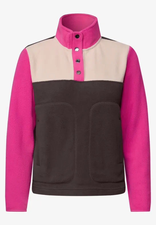 Fleecejacke mit hohem Stehkragen, Knopfleiste, pinken Ärmeln, beigen Schulterpartie und dunkelbraunem Vorderteil.