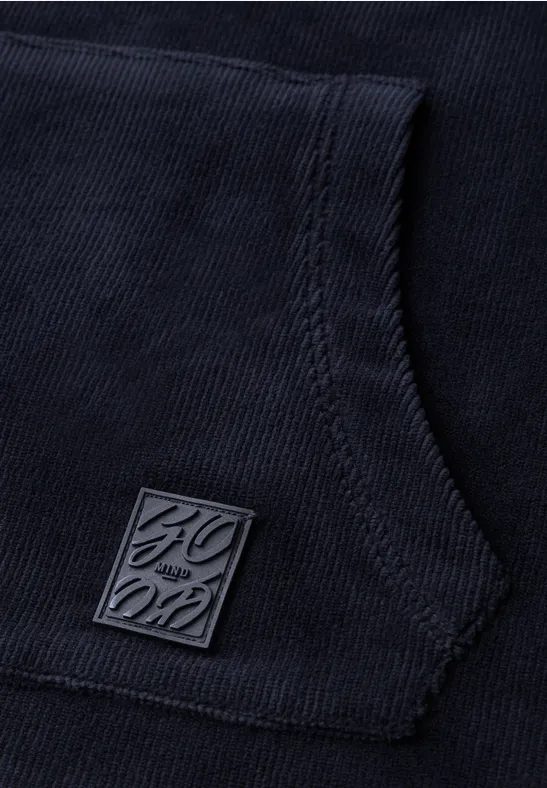 Nahaufnahme einer dunkelblauen Kapuzenjacke mit Kängurutasche und quadratischem Metall-Logo