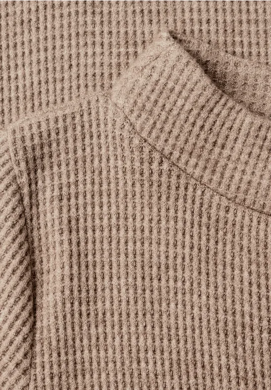 Pull en maille beige à col roulé et motif épais.