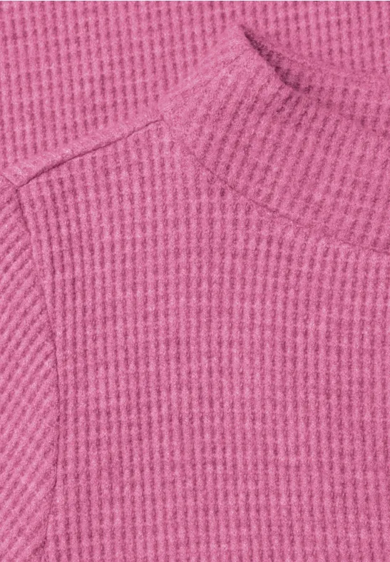 Rosa gerippter Pullover mit Rollkragen-Ausschnitt.