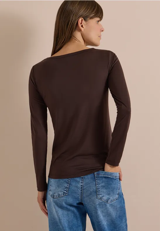Frau von hinten trägt ein braunes Langarmshirt und blaue Jeans.