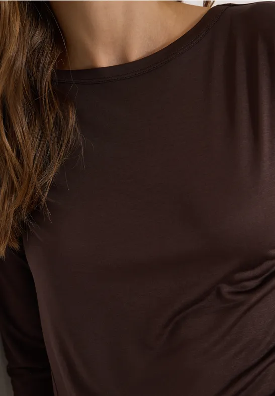 Nahaufnahme eines Oberkörpers in braunem Langarmshirt mit sichtbaren Haaren.