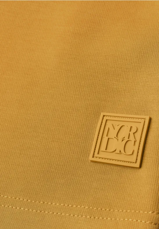 Senfgelber Stoff mit quadratischem Y.R.C.C.-Logo-Patch in Nahaufnahme.