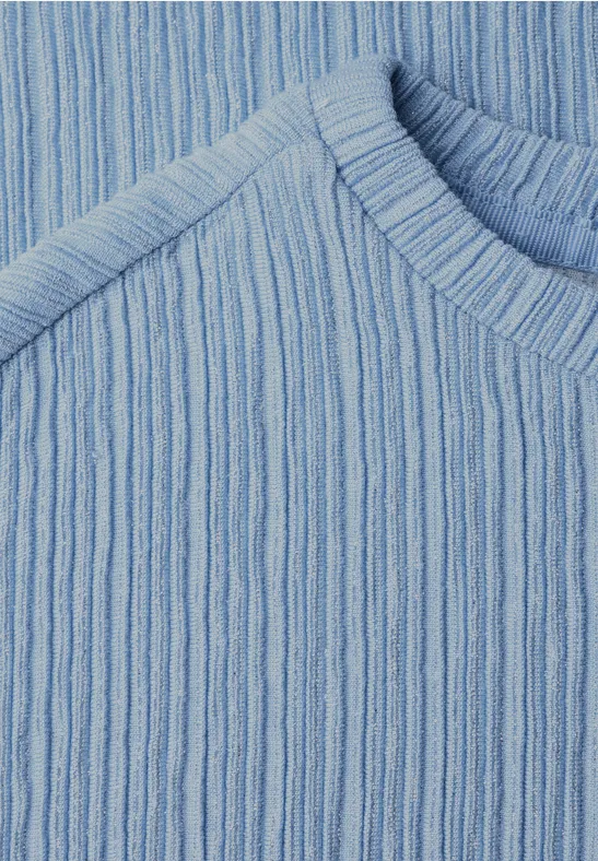 Gros plan sur un pull en maille côtelée bleu clair.