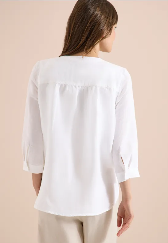 Frau von hinten in locker sitzender weißer Bluse mit 3/4-Ärmeln.