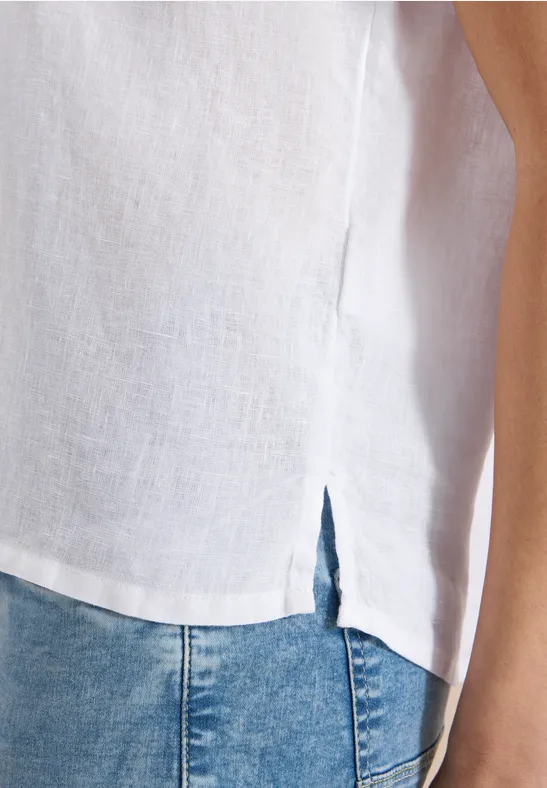 Weiße Leinenbluse mit seitlichem Schlitz, kombiniert mit blauen Jeans.
