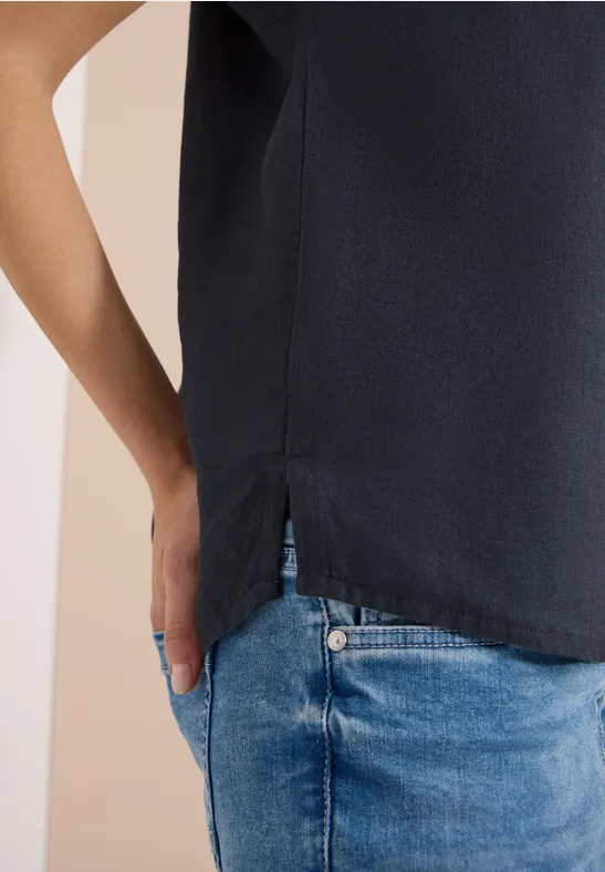 Ein Ausschnitt einer Person in schwarzem Top und blauen Jeans, Hand leicht in der Tasche.