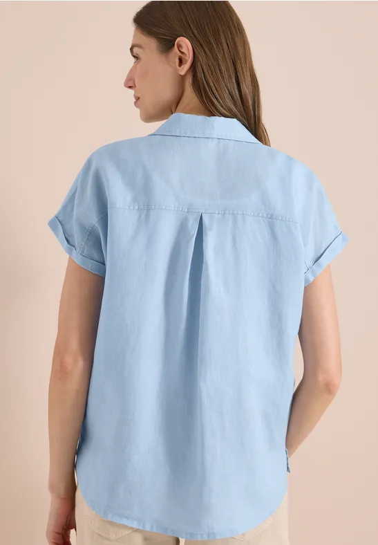 Frau von hinten in locker sitzender, hellblauer Kurzarm-Jeansbluse.