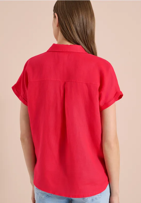 Frau von hinten in einer roten, kurzärmeligen Bluse mit umgeschlagenen Ärmeln