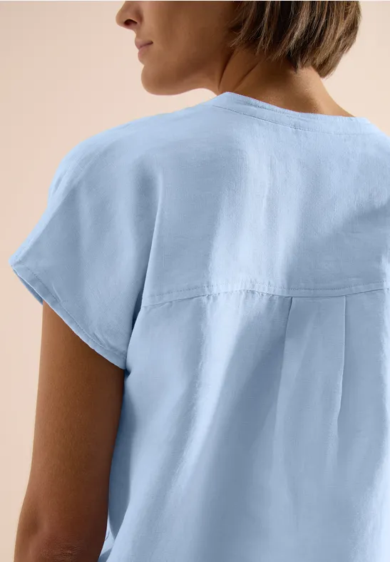 Frau von hinten in hellblauer Bluse mit kurzen Ärmeln und Rückenpasse