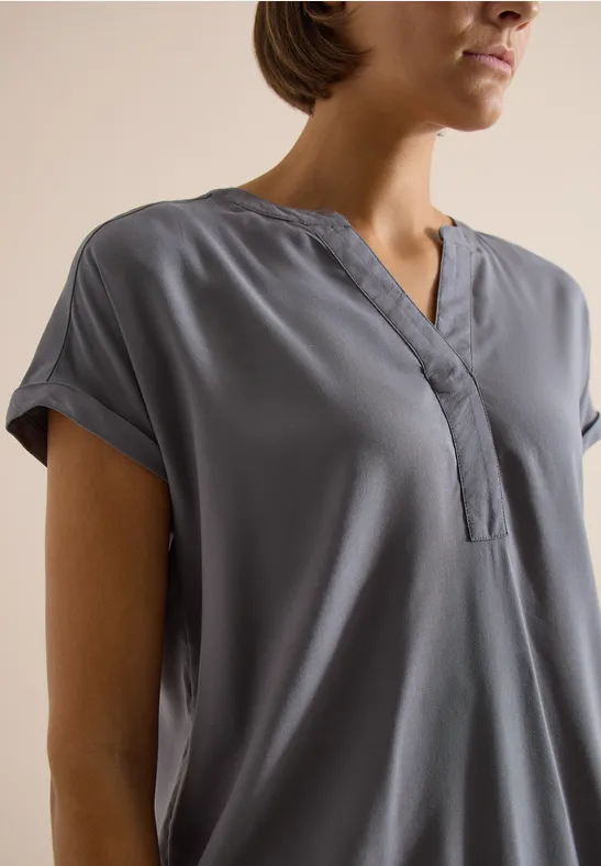 Graue Bluse mit kurzen Ärmeln und V-Ausschnitt, locker sitzend und minimalistisch elegant.