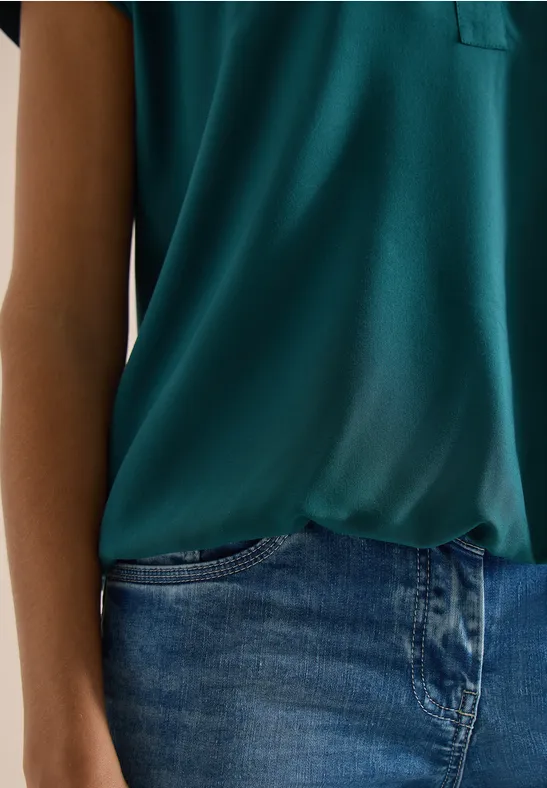 Close-up van een torso met groen shirt en blauwe spijkerbroek