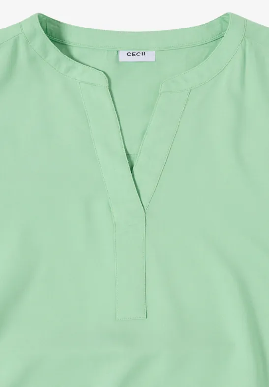 Lichtgroene damestop met V-hals en korte staanderkraag.