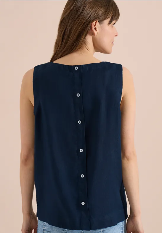Femme de dos portant un top sans manches bleu marine avec boutons dans le dos.