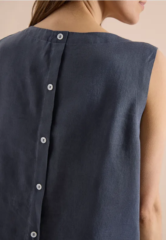 Vue de dos d'une femme portant un haut sans manches en lin bleu marine avec patte de boutonnage au dos.