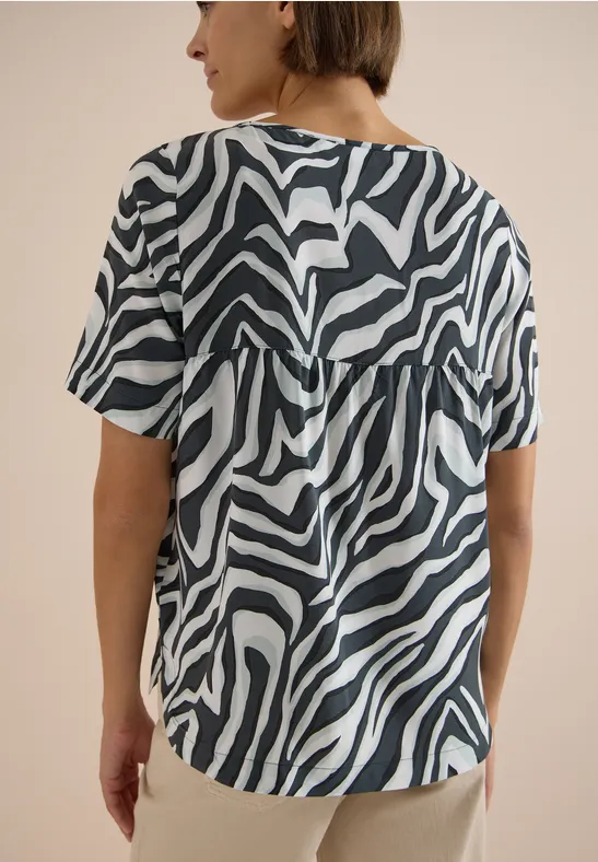 Frau von hinten in kurzärmligem Shirt mit schwarz-weißem Zebramuster.