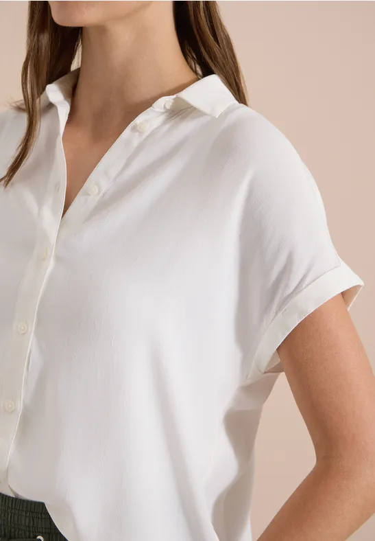 Blouse blanche à manches courtes avec patte de boutonnage fluide.