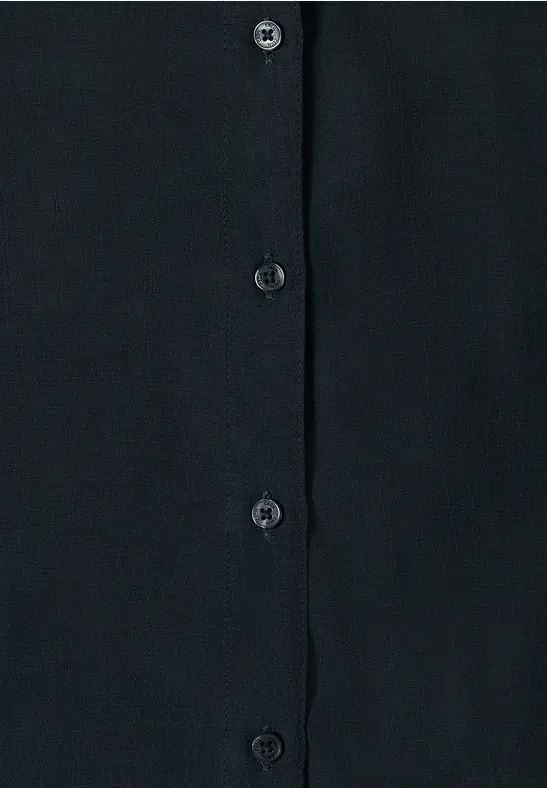 Vêtement noir avec patte de boutonnage et boutons noirs sur tissu sombre.