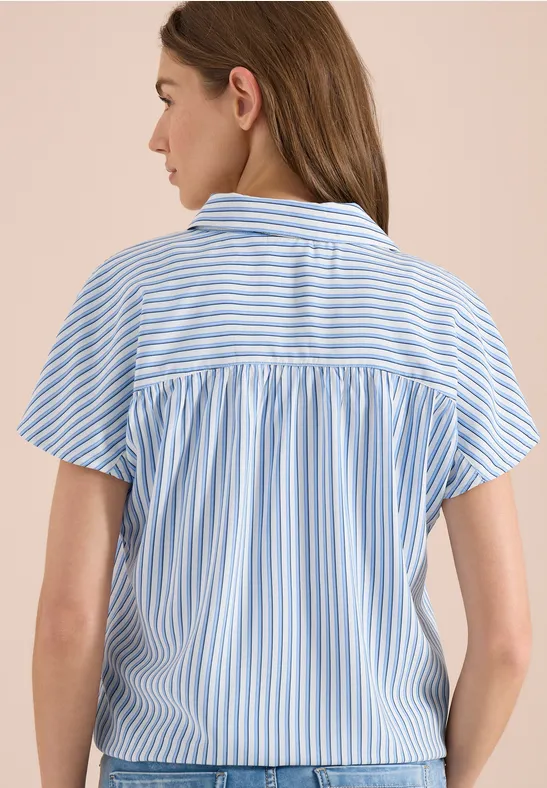 Frau von hinten in blau-weiß gestreiftem Kurzarmhemd mit Rückenpasse und Falten