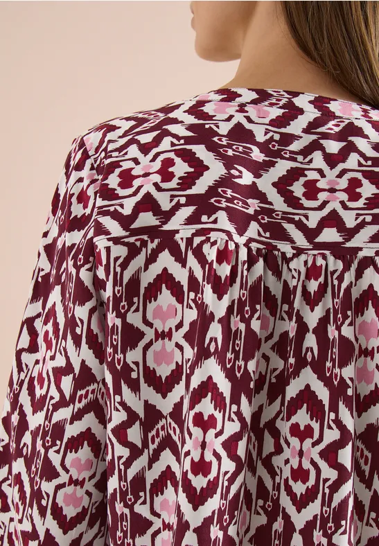 Rückansicht einer fließenden Bluse mit bordeaux-weißem Ikat-Muster.
