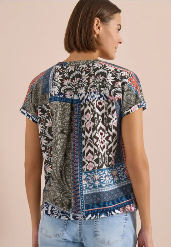 Vrouw van achteren met een gebloemde top en lichte spijkerbroek.