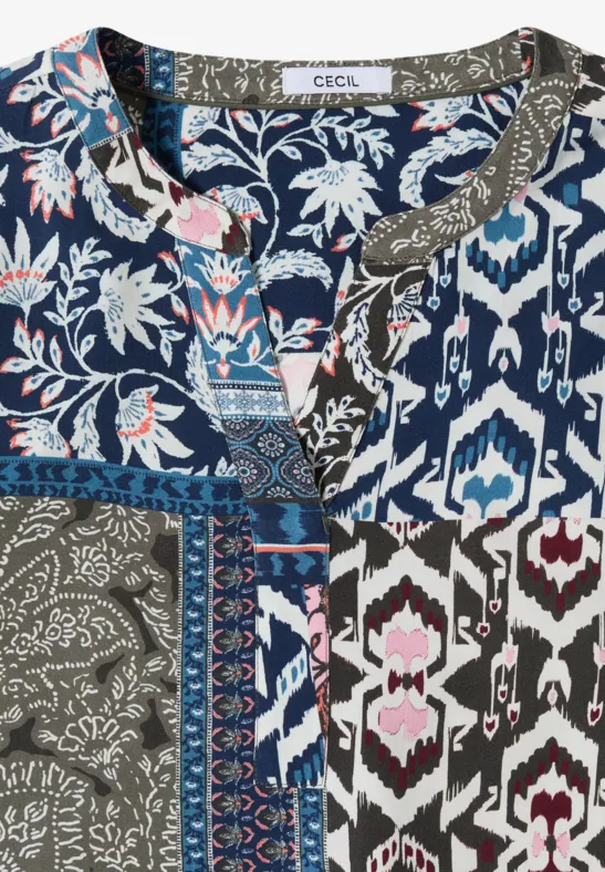 Gekleurde patchworkblouse met bloemen- en geometrische patronen in blauw, wit en olijfgroen.