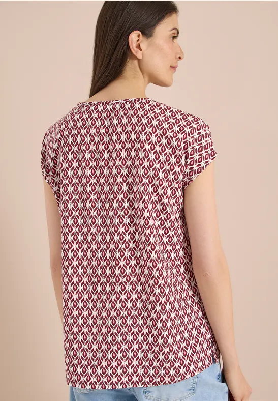 Vrouw van achteren in rood-wit geometrisch dessin T-shirt met korte mouwen voor beige achtergrond.
