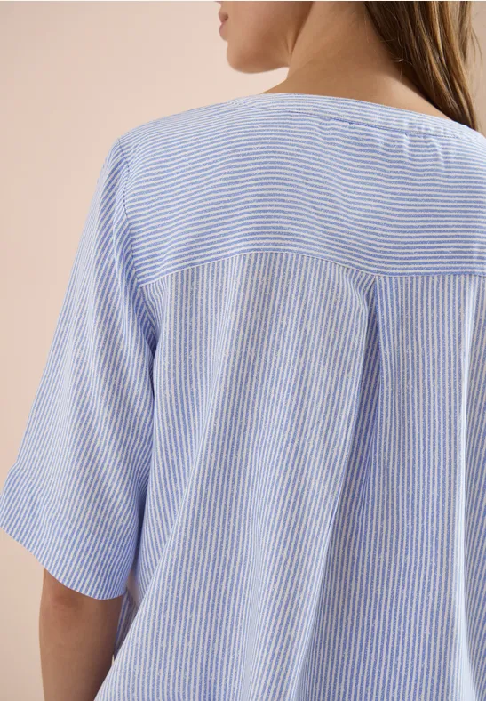 Achteraanzicht van een vrouw in een lichtblauw, fijn gestreept T-shirt met korte mouwen