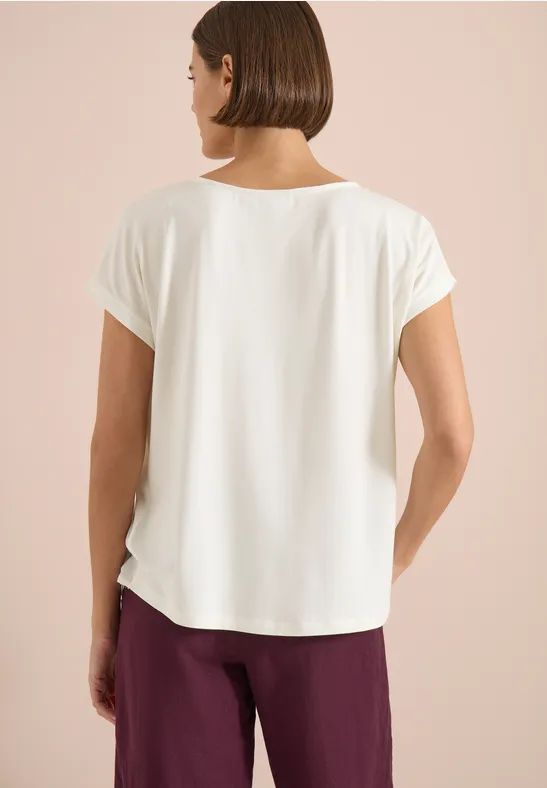 Frau von hinten in weißem Kurzarmshirt und weinroter Hose