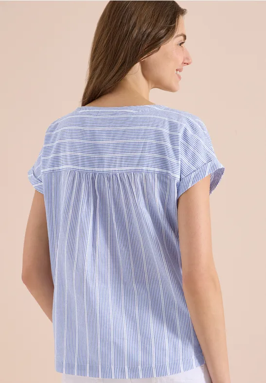 Junge Frau von hinten in hellblauer, weiß gestreifter Bluse mit kurzen Ärmeln.