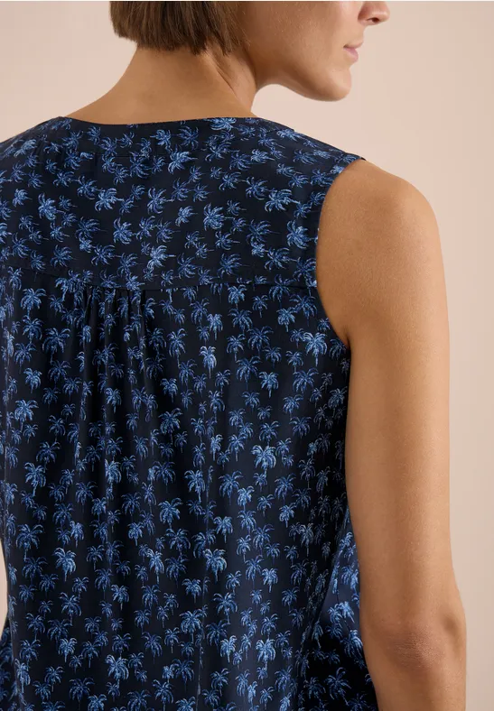 Femme de dos portant un haut sans manches bleu foncé à fleurs bleues et un pli dans le dos.
