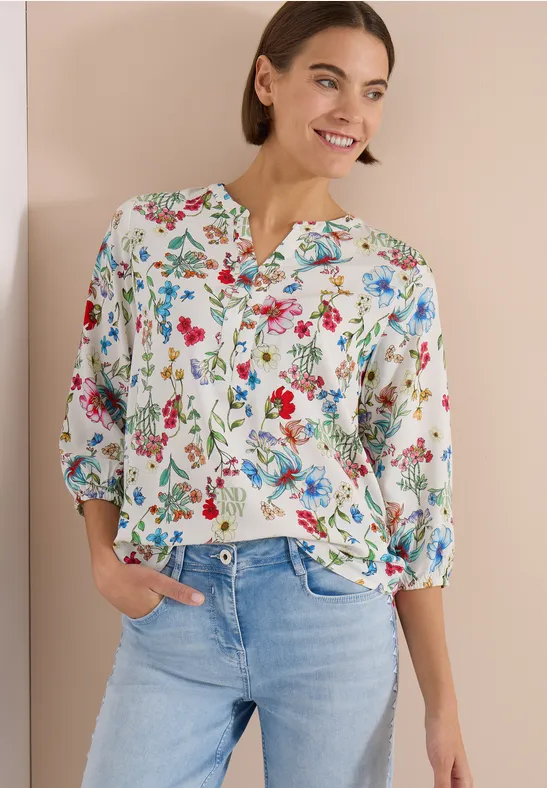 Femme en chemisier blanc à fleurs et jean bleu clair