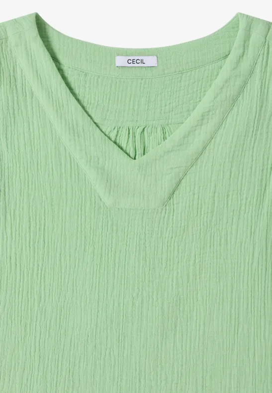 Ein hellgrünes Damen-Shirt mit V-Ausschnitt und strukturierter Rippoptik, kurz geschnitten und lässig.