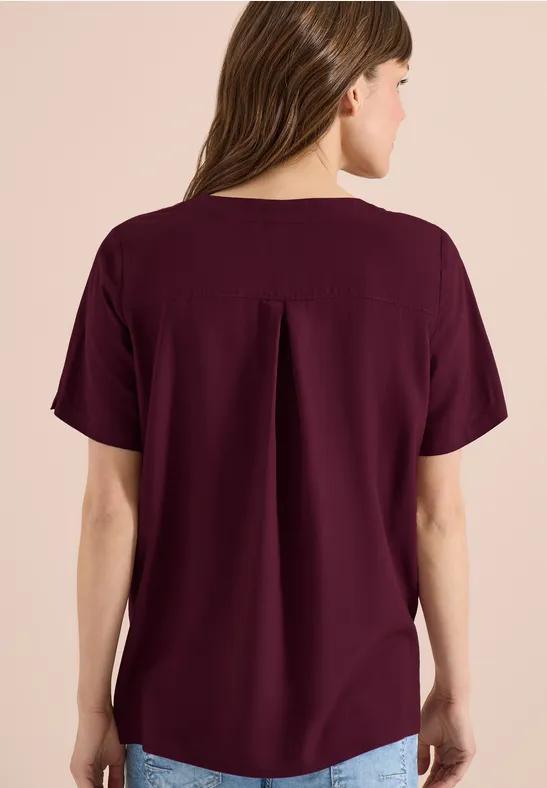 Rückenansicht einer Frau in lockerem, kurzärmligem, burgunderrotem Oberteil