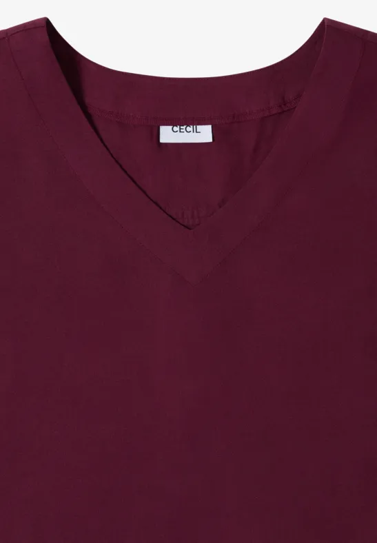 Ein schlichtes, dunkelrotes V-Neck-Shirt, flach liegend.