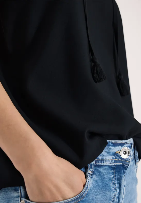 Person mit schwarzem Oberteil, Hand in hellblauer Jeans-Tasche