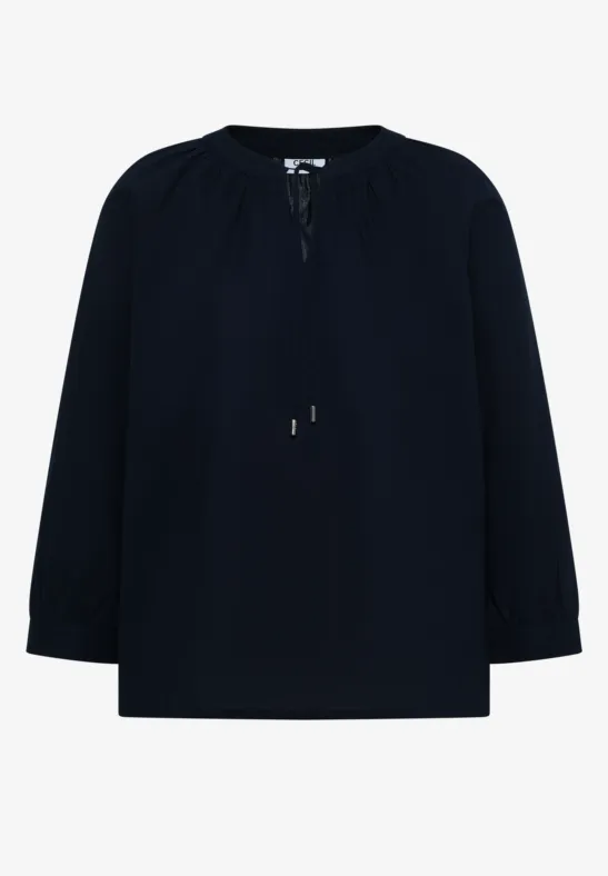 Schlichte dunkelblaue Bluse mit langen Ärmeln und Kordelzug am Ausschnitt.