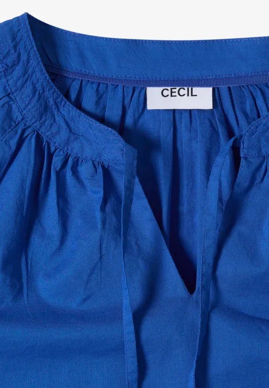 Blaue Damenbluse mit weitem, gerafftem Ausschnitt und innenliegendem Etikett 'CECIL'.