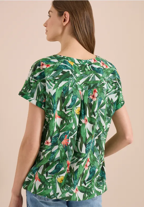 Vrouw van achter in korte mouw blouse met groene bladerenprint.